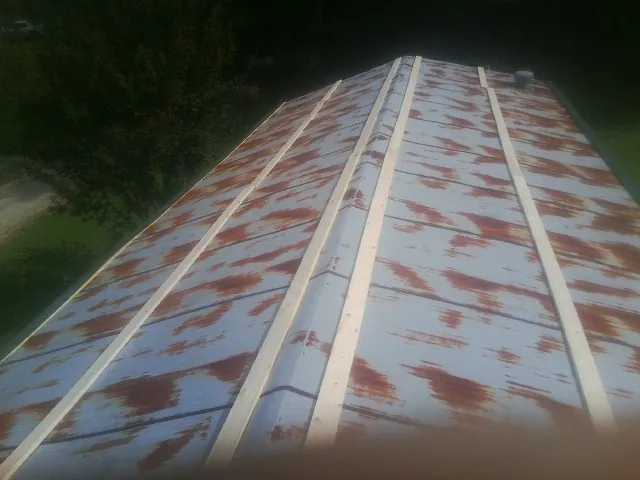 Rusted metal roof panels with new wood purlins before replacement — Storm Damage Roof Repair in Keenesburg by Roofing Brothers