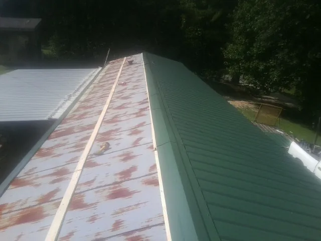 Old rusted panels beside newly installed green metal roofing — Wind Damage Roof Repair by Roofing Brothers in Keenesburg
