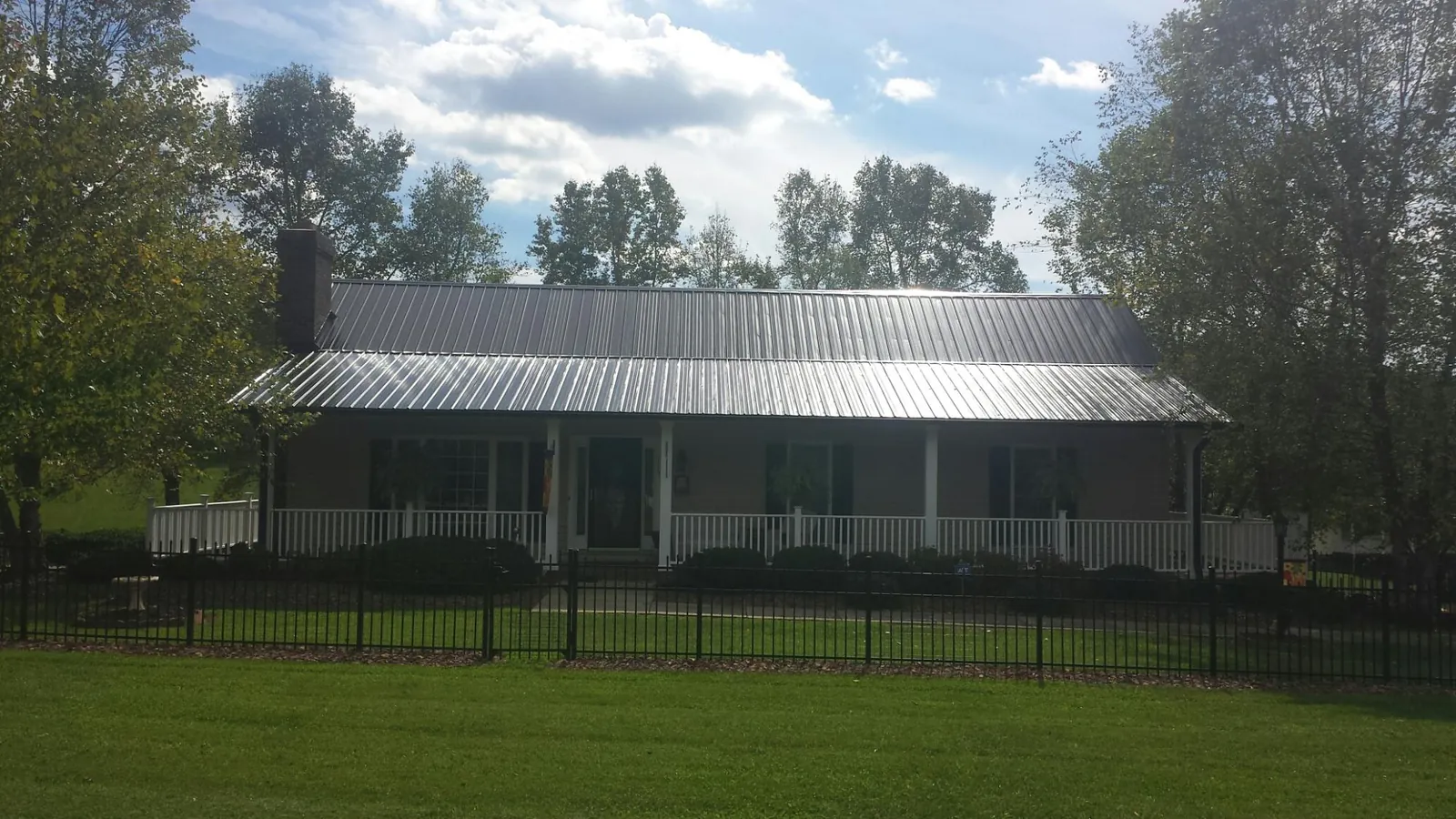 Gray metal roof on a brick ranch with a full width front porch — Gutter Guard Installation work by our crew in Keenesburg